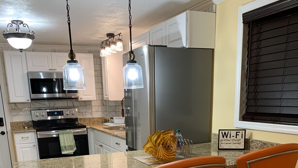 A modern kitchen with a central island, stainless steel appliances, and a 'Wi-Fi' sign. - Sunshine Villa One (Jacksonville)
