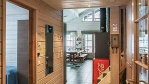Et træpanelt interiør med trappe, et Coca-Cola køleskab og et spiseområde med bænke.