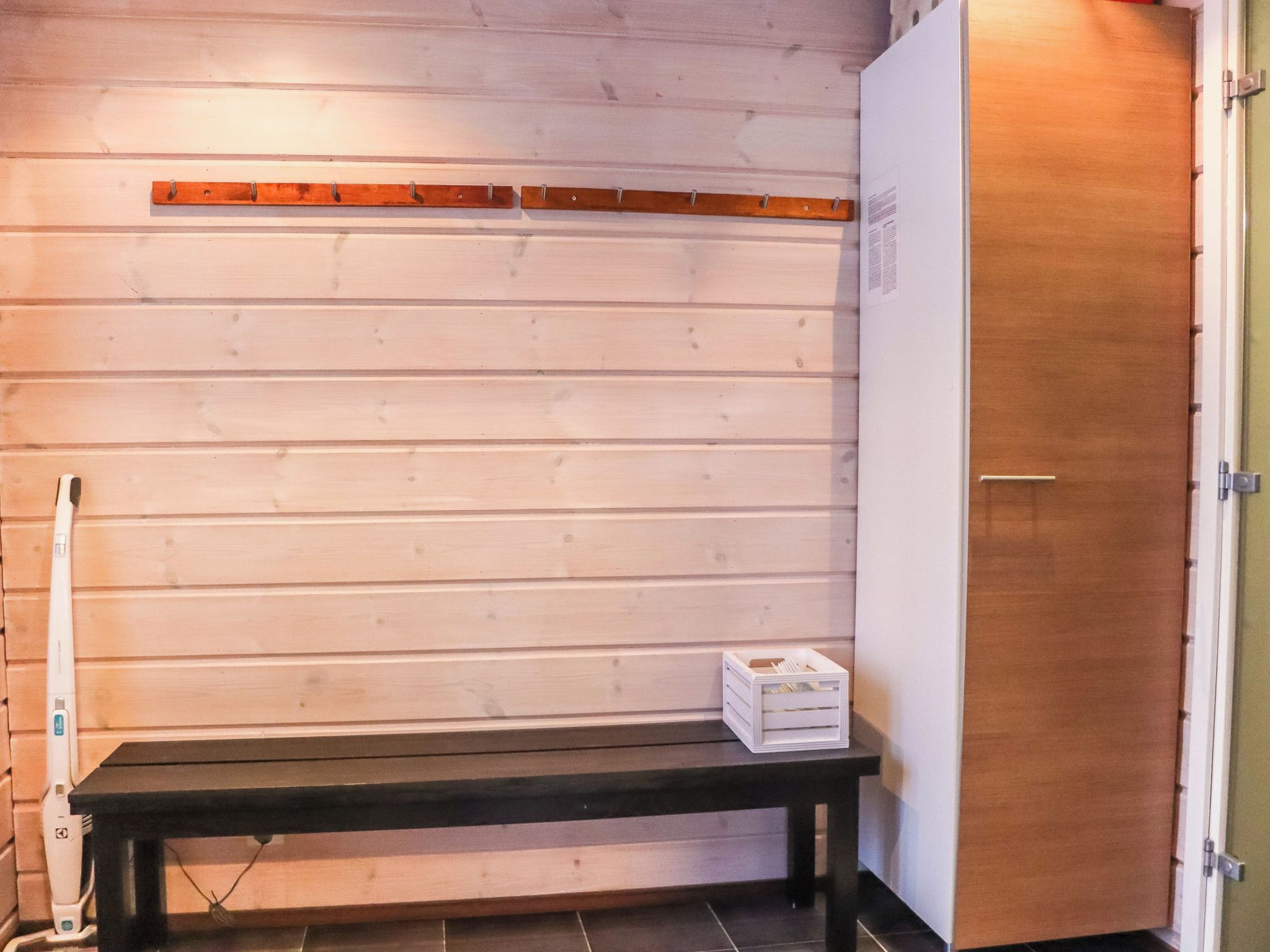 Una sala de sauna con un banco, un estante de madera y una puerta.