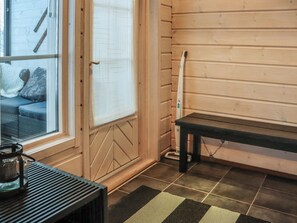 Un sauna équipé d’un banc, d’une porte vitrée donnant sur un espace détente et d’un sol carrelé.