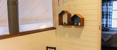 A cozy room with a wooden ceiling, a small table, chairs, and a pet bed with a dog.