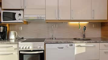 A kitchen with white cabinets, a microwave, a stove, a dishwasher, and a sink.