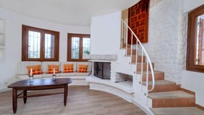 A spacious living room with a curved staircase, a fireplace, and a sofa set. - Hercaris by Interhome (Begur)