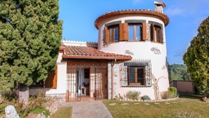 A two-story house with a circular tower, stone pathway, and a statue in the garden. - Hercaris by Interhome (Begur)