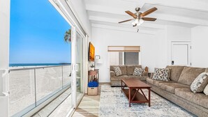 A balcony with a view of the beach, a ceiling fan, a sofa, and a coffee table. - Spectacular Ocean Views at Affordable Prices | Super Central | Walk to Everything! (Newport Beach)