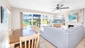 A spacious living area with a dining table, sofa, and a ceiling fan.