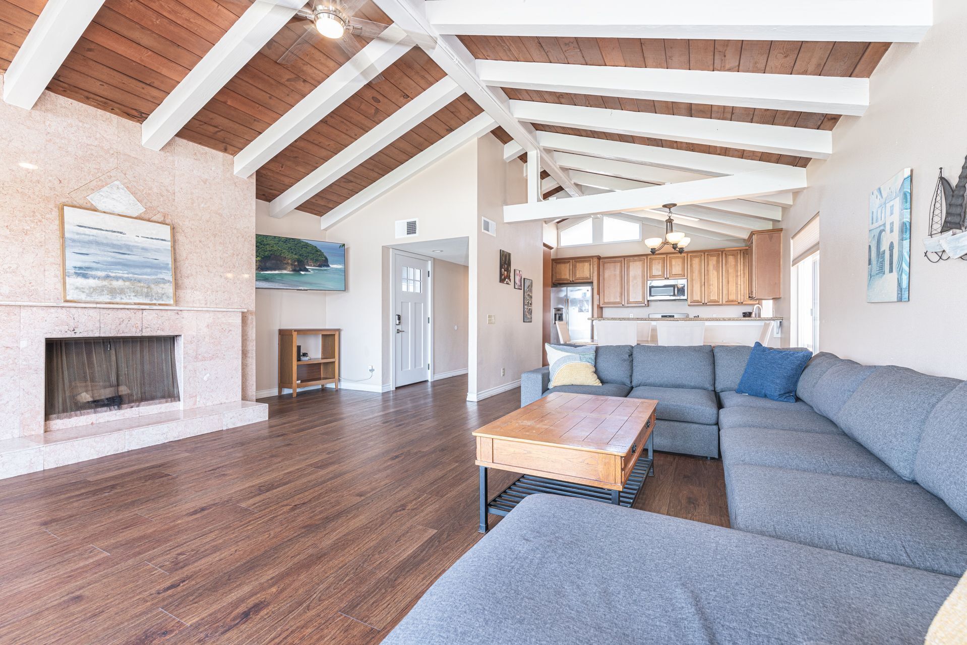 A spacious living room with a fireplace, a large gray sectional sofa, and a wooden coffee table.