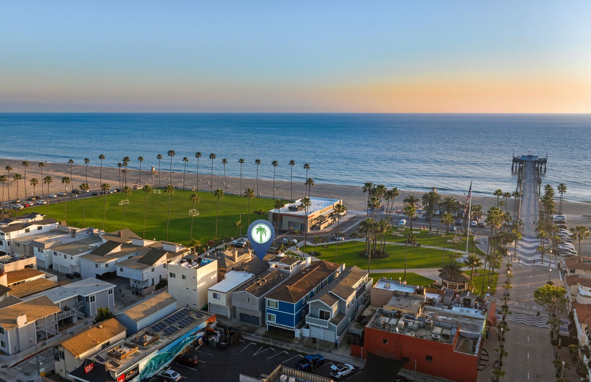 A coastal residential area with houses, a beach, and a pier.