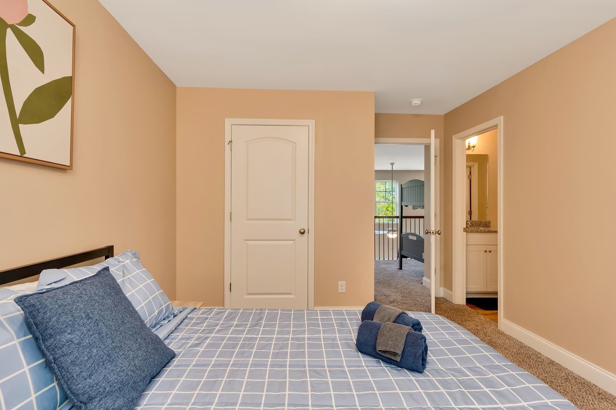 A bedroom with a bed, a door, and a view of a balcony.