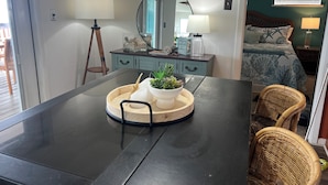 A modern room with a dark wooden table, a round mirror, and a bed with a blue ocean-themed bedspread. - AWESOME VIEW... On Private Gulf of Mexico Beach... Majestic Views  🐢🌴🌞 (Alligator Point)