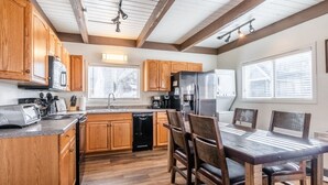 Una cocina con armarios de madera, una mesa de comedor con sillas, un refrigerador y un lavavajillas.