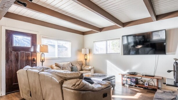 Una sala de estar con un sofá modular, un televisor de pantalla plana montado en la pared y una chimenea.