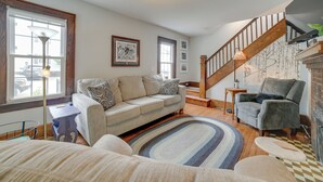 Una sala de estar acogedora con sofá, sillón, escalera y chimenea.