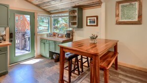 Una cocina con armarios de madera, una mesa de comedor con bancos y vistas al exterior.