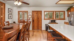 A kitchen with wooden cabinets, a stainless steel refrigerator, a microwave, and a large island with bar stools.