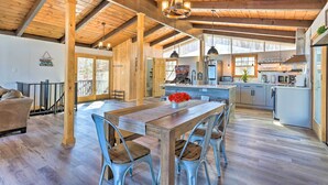 A spacious kitchen with wooden beams, a dining area with a large table, and a view of the outdoors. - Lake Escape In the Poconos (Pocono Lake)