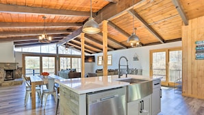 A spacious kitchen with a large island, wooden beams, and a stone fireplace. - Lake Escape In the Poconos (Pocono Lake)
