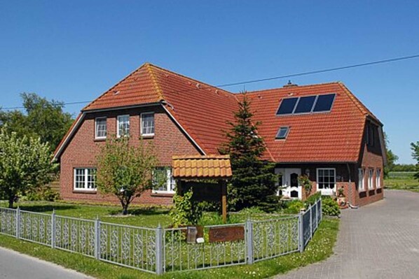 A two-story brick house with a red-tiled roof, a small attached garage, and a fenced yard.