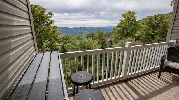 A balcony with a white railing, a wooden table, and a small round table.