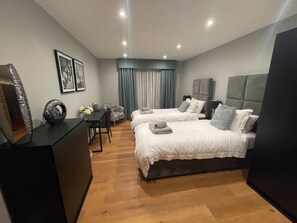 Ein modernes Hotelzimmer mit zwei Betten, einem Schreibtisch und einem Stuhl.