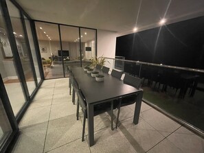 A modern dining area with a long table, chairs, and potted plants. - Ancarva - Contemporary Waterside Holiday Retreat (Torpoint)