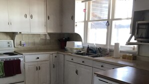 A kitchen with white cabinets, a stove, a sink, a dishwasher, and a window with a view of the outside. - Sunset on the Ottawa "Cottage"- shallow, silky sandy beach w/ 78-84 F warm water (Pembroke)