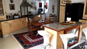 Een moderne keuken met houten kastjes, een granieten aanrecht, een centraal eiland met barkrukken, en een vloerkleed met een patroon.