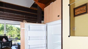 Eine moderne Küche mit Einbaukühlschrank, Holzbalkendecke und einem Essbereich, der durch eine offene Tür sichtbar ist.
