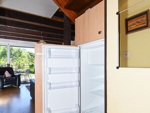 Eine moderne Küche mit Einbaukühlschrank, Holzbalkendecke und einem Essbereich, der durch eine offene Tür sichtbar ist.