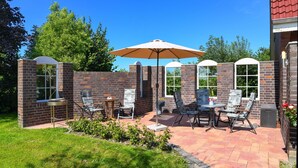 Ein Patio mit Ziegelmauern, Gartenmöbeln und einem großen Sonnenschirm.