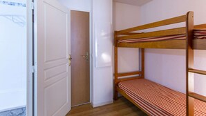 A small, single-room apartment with a bunk bed, a white door, and a wooden floor. - Studio cabin, pets allowed - 4 guests (La Mongie)