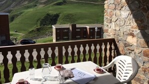 A table set outdoors with a mountain view, a stone wall, and a wooden railing. - Studio cabin, pets allowed - 4 guests (La Mongie)