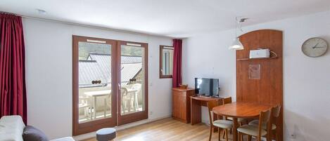 Una habitación pequeña con cama, una mesita, televisión y zona de comedor.