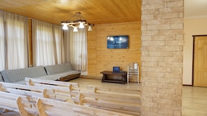A wooden interior with a sofa, a television, and a stone wall.