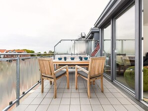 Ein Balkon mit Tisch und Stühlen mit Blick auf ein Gewässer und Gebäude.