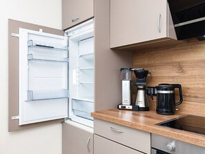 Et åbent køleskab med kaffemaskine og vanddispenser på bordet.