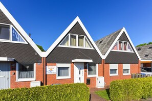A row of red brick houses with white trim, each with a pitched roof and a small front porch.