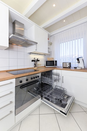 Een moderne keuken met witte kastjes, roestvrijstalen apparatuur en een houten aanrecht.