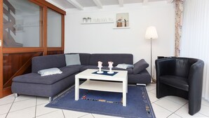 Un salon moderne avec un canapé gris, une table basse blanche, un fauteuil noir et un tapis bleu.