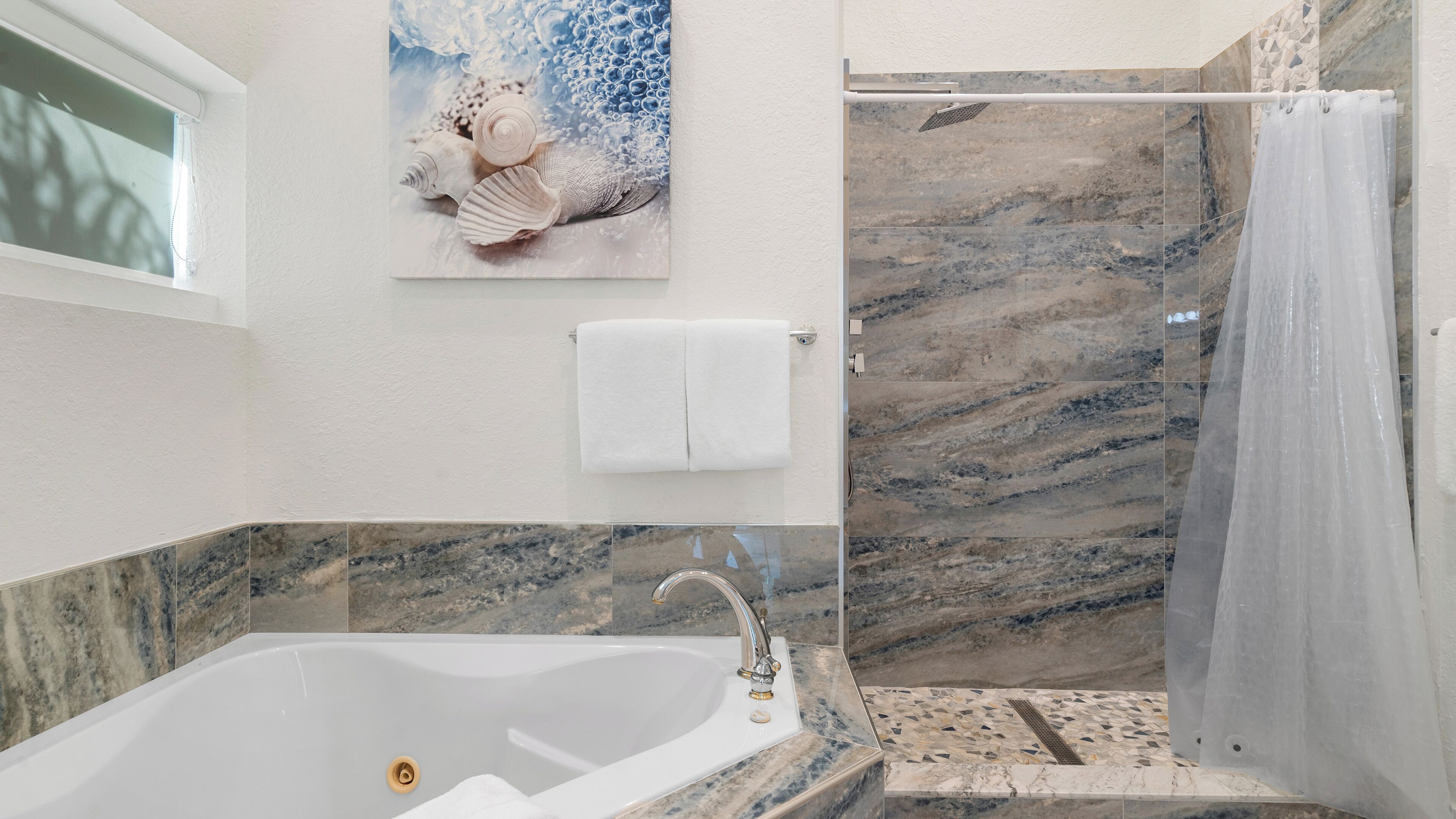 A bathroom with a bathtub, a shower, and a towel rack.