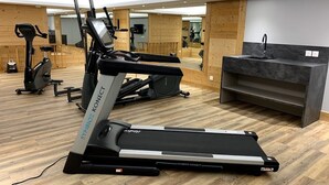 Un gimnasio con cintas de correr, un espejo y un lavamanos.