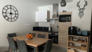 Una cocina moderna con comedor, que incluye un reloj, un microondas y una cafetera.