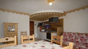 Une pièce chaleureuse avec une table à manger en bois, des chaises, un canapé et un coin cuisine.