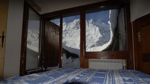Une chambre avec une grande fenêtre donnant sur des montagnes enneigées.
