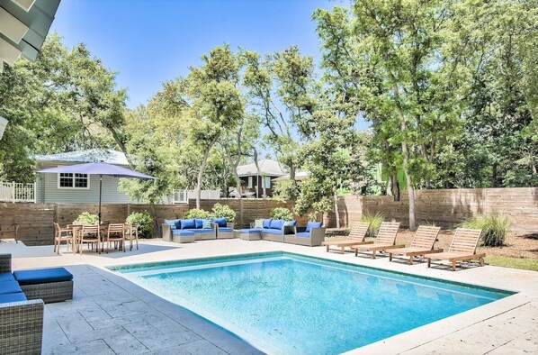 Un jardin avec une piscine, du mobilier d’extérieur et une clôture en bois.