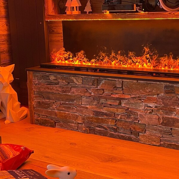 A fireplace with a stone surround and a wooden mantel. - 80 m2, ski in / out center Alpe d'huez, luxury 8p 3bdrm 3bathroom 3 terraces with fireplace SPOT (ALPE D HUEZ)