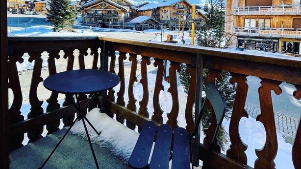 A balcony with a table and chairs, overlooking a snowy mountain and buildings. - 80 m2, ski in / out center Alpe d'huez, luxury 8p 3bdrm 3bathroom 3 terraces with fireplace SPOT (ALPE D HUEZ)
