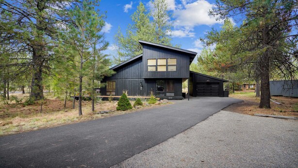 A modern two-story cabin with a dark exterior, a garage, and a driveway leading to the entrance. - 1 Crag-Sunriver, Oregon: Hot Tub, Pet Friendly, BBQ, WiFi, SHARC Aquatics, Tubing Hill, Mt. Bachelor, Golf, Deschutes River, Tennis, Bike Paths (Sunriver)