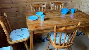 A wooden dining table with chairs, a hanging light fixture, and a religious icon on the wall. - Ferienhaus mit Kachelofen (Grafenau)