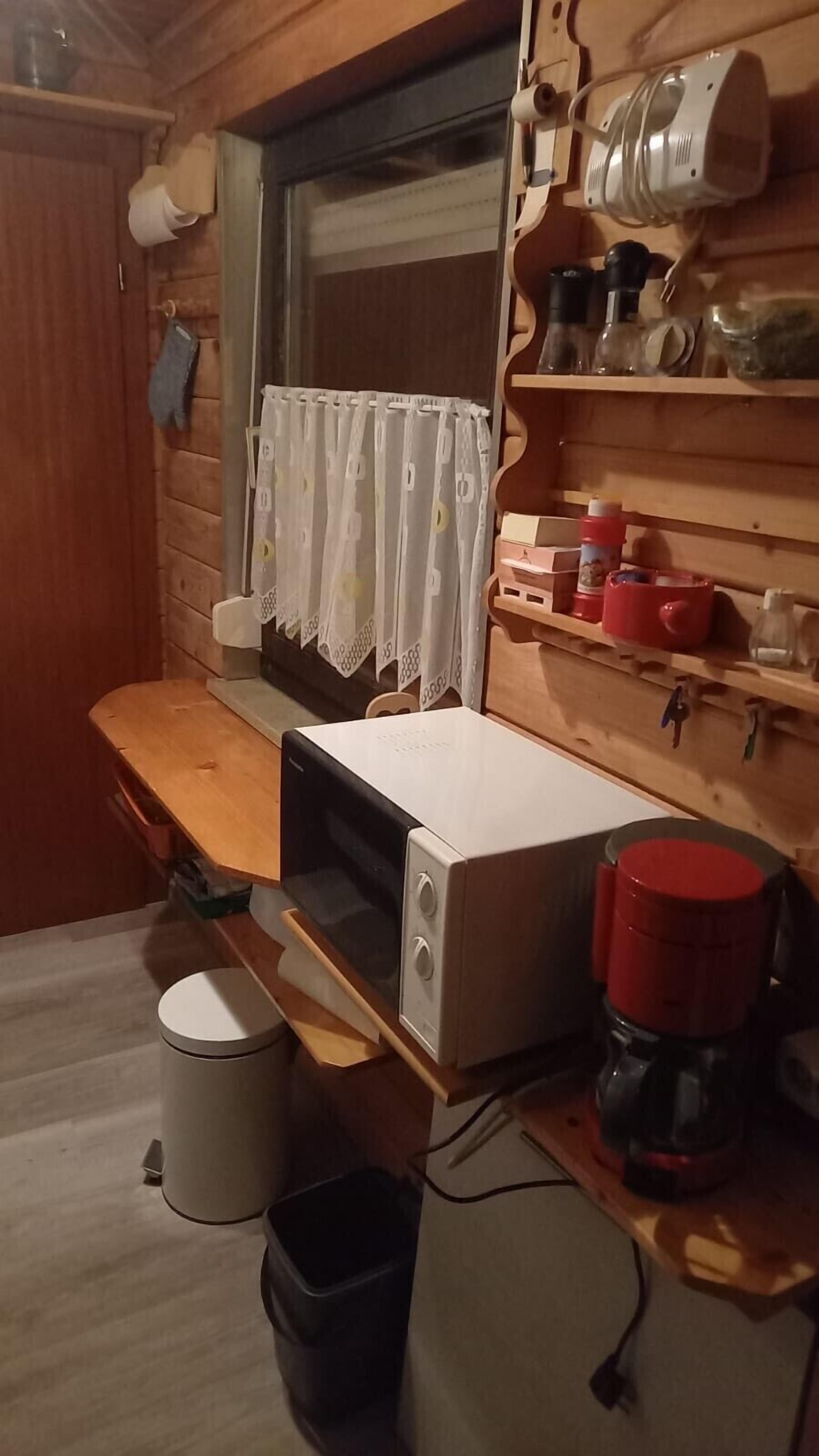 Eine kompakte Küche mit Mikrowelle, Kaffeemaschine und kleinem Spülbecken.